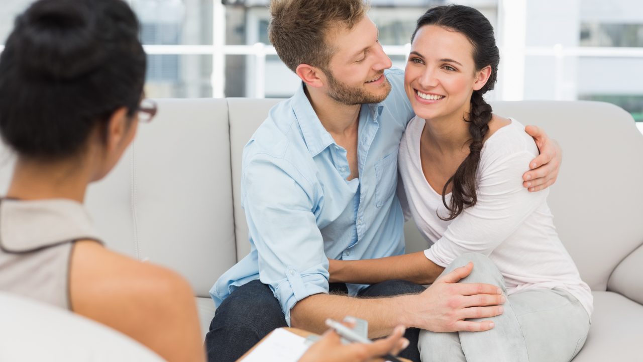 Happy couple reconciling at therapy session in therapists office